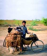Indick cyklista, pevejc nklad z vesnice do vesnice. Pod rmem m v placht kozu - ivou konzervu.